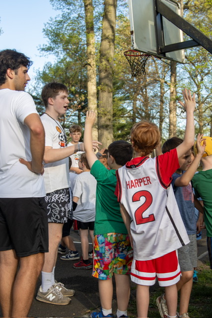 Sitter high-fiving kids at basketball hoop