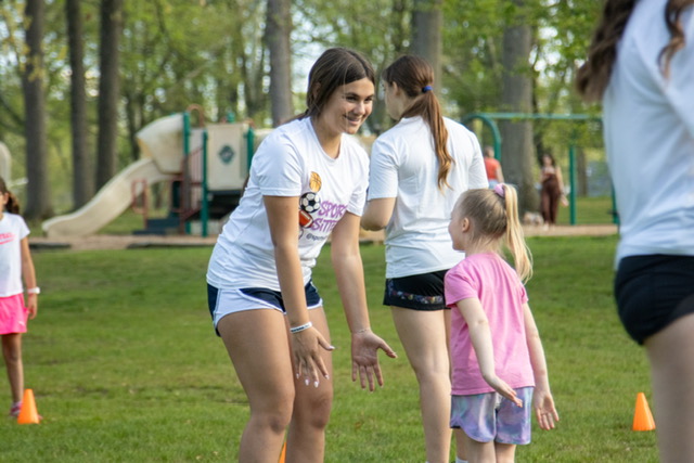 Sports Sitter coaching soccer with young girl