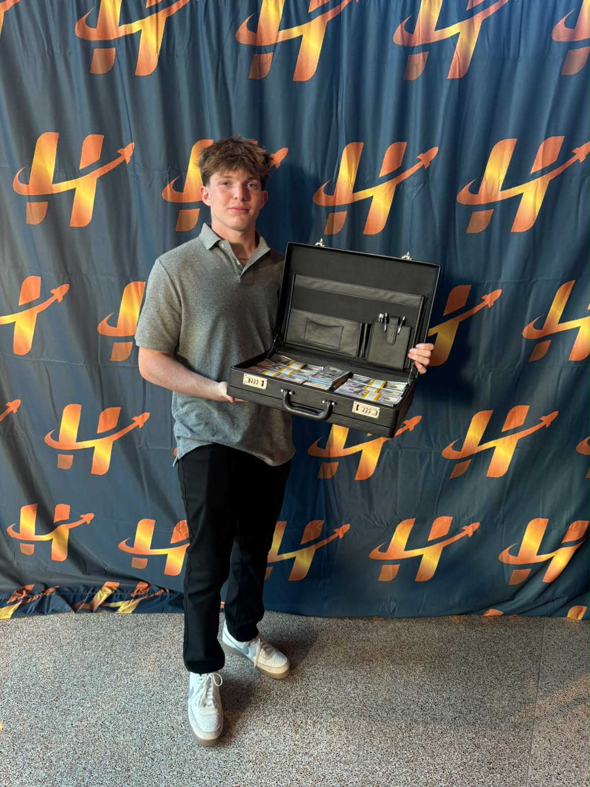 Cody DeCoons holding a briefcase at the High School Hustle Awards Ceremony