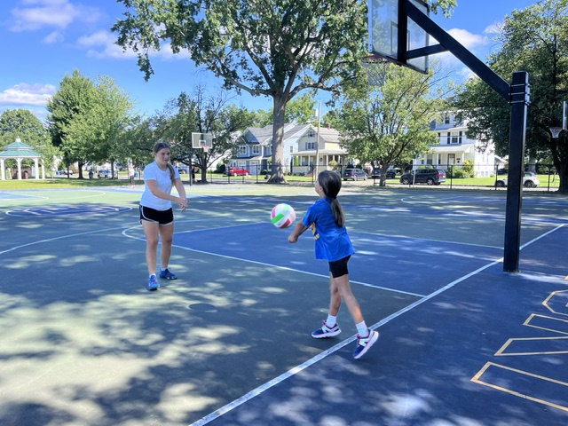 Sports Sitter and young athlete with a basketball at the park