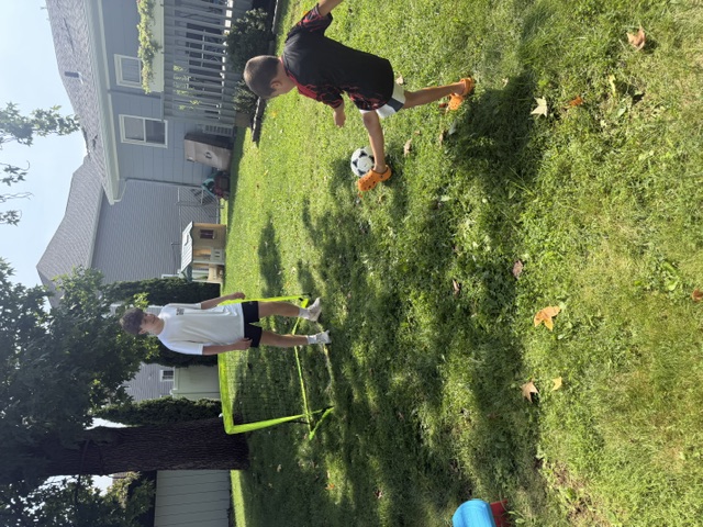 Sports Sitter running a one-on-one soccer drill in the backyard